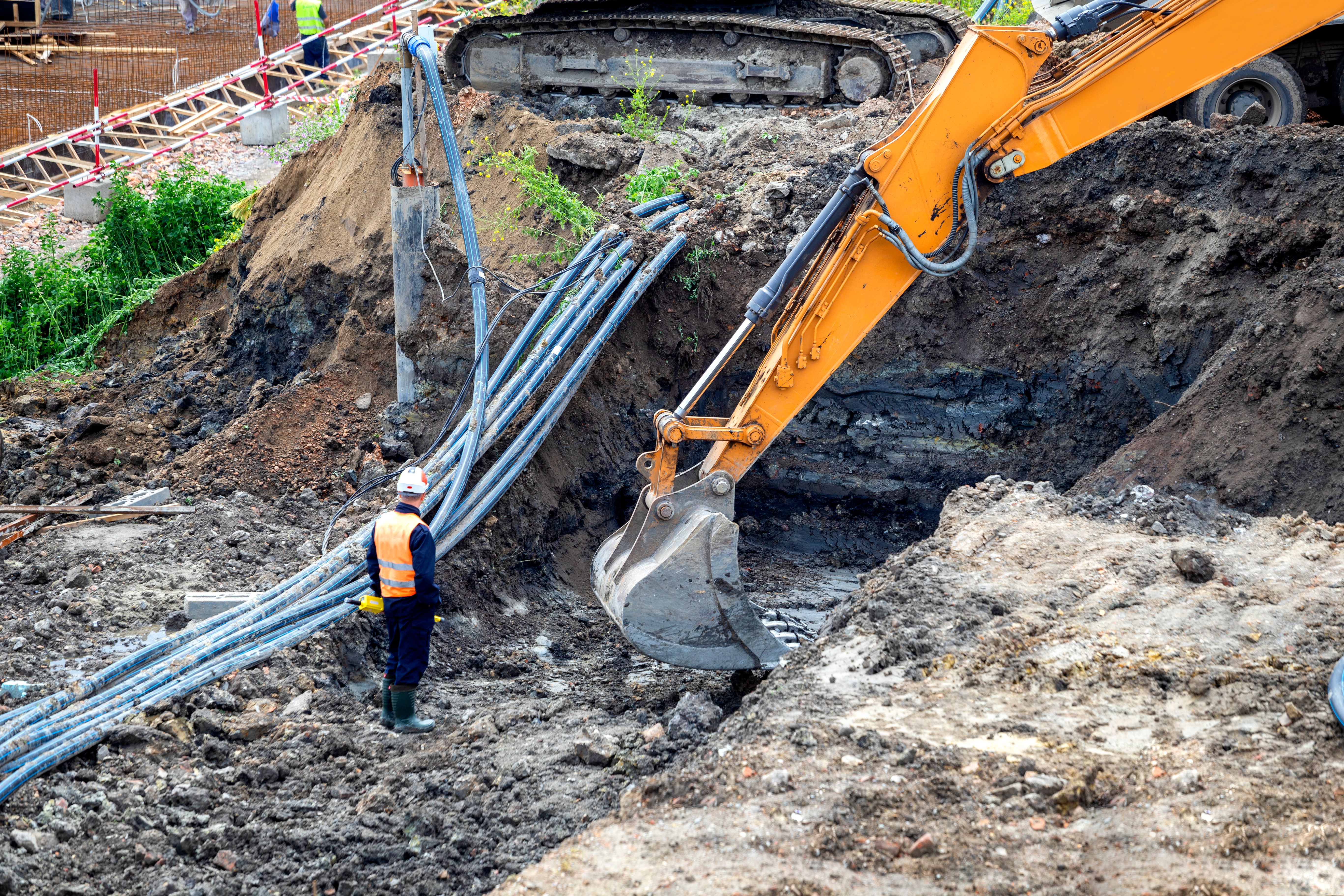 Excavation crew performing underground utility work with heavy equipment